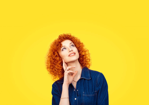 Woman daydreaming. Thinking. Closeup portrait redhead curly happy mixed race daydreaming smiling cute confident latin female girl businesswoman isolated yellow background wall. Positive human emotion  - Φωτογραφία, εικόνα