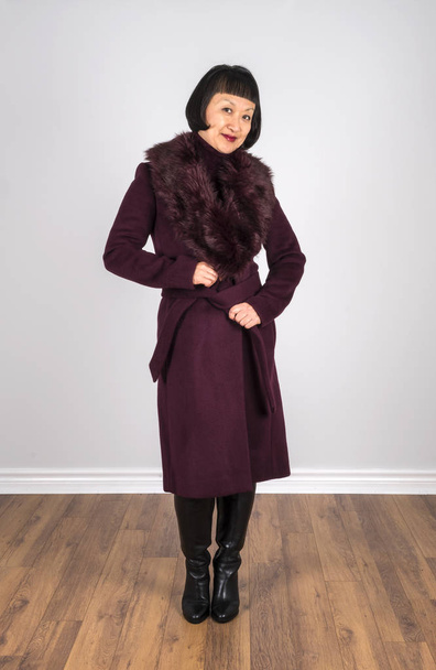 Східна жінка з коротким чорним волоссям у бургундському кольоровому вовняному пальто, що позує для камери
 - Фото, зображення