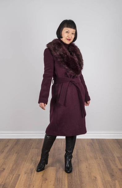 Mujer oriental con el pelo corto y negro con un abrigo de lana de color burdeos posando para la cámara
 - Foto, imagen