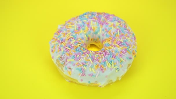 Délicieux donut sucré tournant sur une assiette. Vue de dessus. Lumineux et coloré saupoudré donut gros plan macro tournage sur un fond jaune
. - Séquence, vidéo