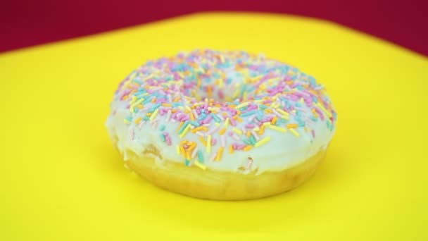 Délicieux donut sucré tournant sur une assiette. Vue de dessus. Lumineux et coloré saupoudré donut gros plan macro tournage sur un fond jaune
. - Séquence, vidéo