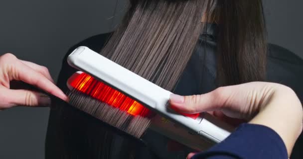 Ręce kobiety zrobić włosy zapisać procedurę. Elektryczny instrument regeneracji włosów z czerwony neon light - Materiał filmowy, wideo