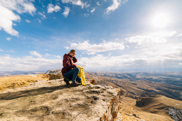 ενεργό νεαρό κορίτσι αγαπά αθλητικού τουρισμού, κάθεται στην άκρη του βουνού στις ακτίνες του ήλιου - Φωτογραφία, εικόνα