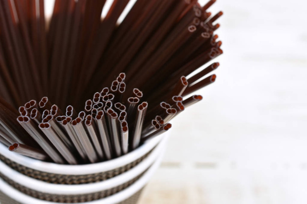 A close up image of brown plastic stir sticks in a disposable coffee cup with a white background.  - Photo, Image