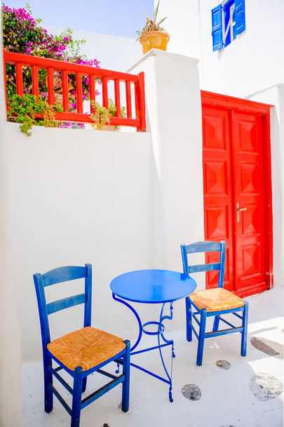 ミコノス島、ヨーロッパの典型的なギリシャの伝統的な村のストリートに青い椅子と屋外カフェ - 写真・画像