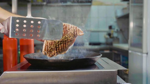 Soft focus of cook turns up a steak of meat on a grill - Fotoğraf, Görsel