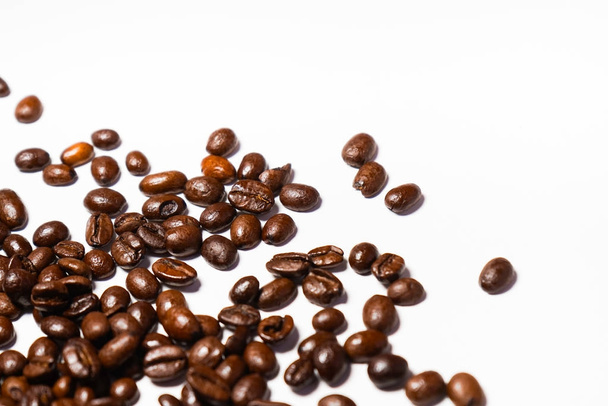 grains of roasted coffee scattered over white background - Foto, afbeelding