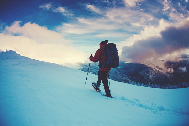 Ένας άνθρωπος με χιονοπέδιλα στα βουνά. - Φωτογραφία, εικόνα