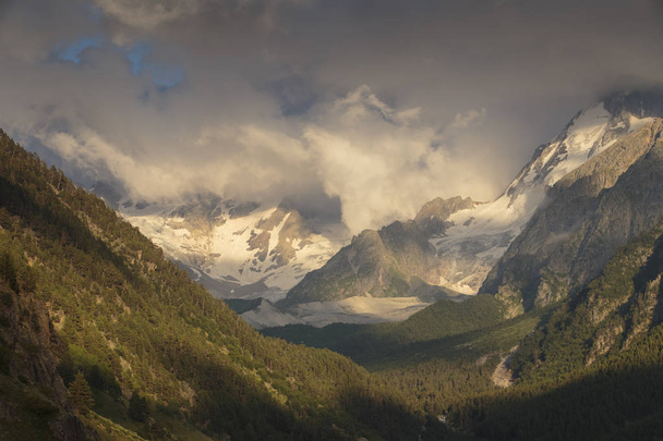 Vue estivale sur les montagnes enneigées du Caucase. Formation et déplacement des nuages sur les sommets des montagnes
. - Photo, image