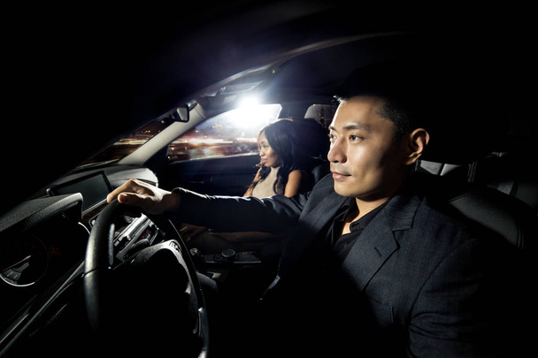 Asian Mężczyzna jadący z Czarnej Afryki Data kobiece w samochodzie. Wyglądają, jak idą do klubu nocnego na clubbing kluby nocne. Obraz przedstawia interracial relacje i styl życia. - Zdjęcie, obraz