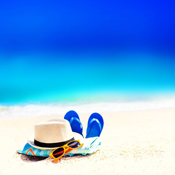 Summer fun time and accessories on a sand on the beach. Blue  sandal flip flop on the white sand with blue sea and sky in summer vacations, copy space - Foto, Imagen