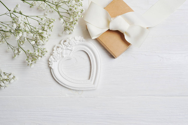 Mock up Composición de flores blancas de estilo rústico, corazones de amor y un regalo para el Día de San Valentín con un lugar para su texto. Flat lay, maqueta de fotos vista superior
 - Foto, imagen