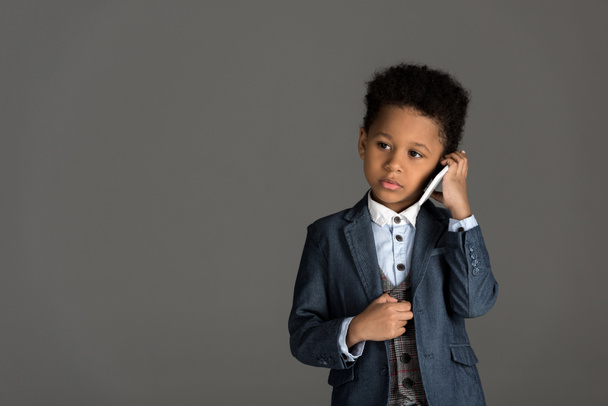 adorable african american kid talking by smartphone isolated on gray - Photo, Image