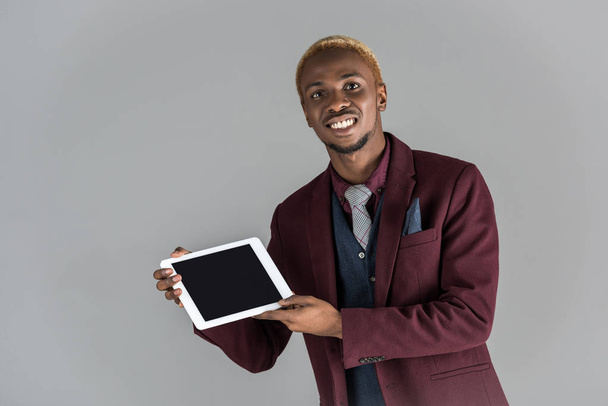 Lächelnder Afrikaner mit digitalem Tablet in der Hand isoliert auf grau - Foto, Bild