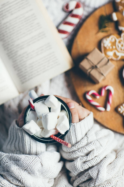 woman with cup of hot chocolate  and  cookies reading book. Top view  - Фото, зображення