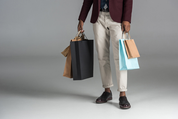 low section of man with paper shopping bags on grey background  - Photo, Image