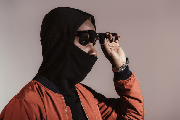Stylish young african american man wearing hood with face mask isolated on light background - Zdjęcie, obraz