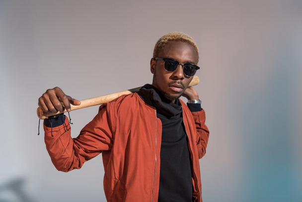 Stylish young african american man holding baseball bat on his shoulders - Foto, imagen