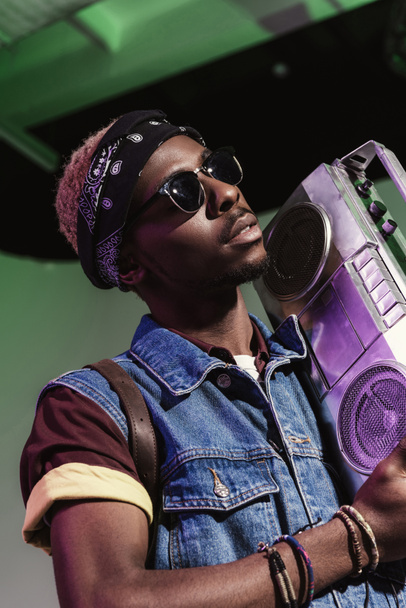 stilvoller junger gutaussehender afrikanisch-amerikanischer Mann mit Sonnenbrille und silbernem Tonbandgerät - Foto, Bild