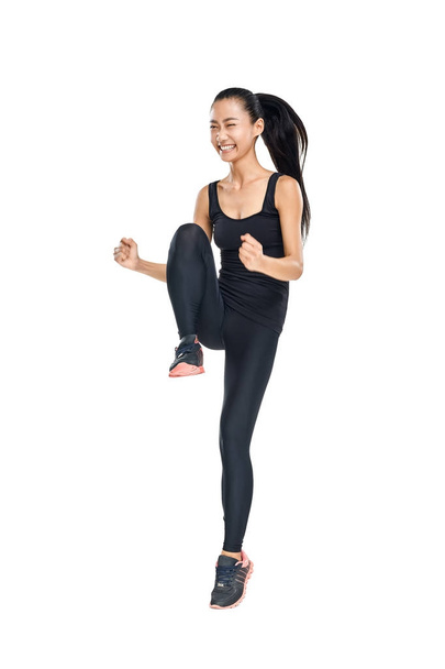 Smiling young Asian athlete jumping up with bent hands - Photo, Image