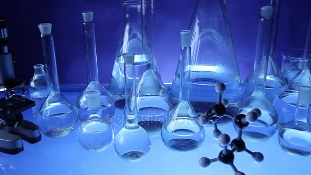 Equipo de laboratorio moderno, conjunto de diferentes cristalería sobre fondo azul. Dolly disparó
. - Metraje, vídeo
