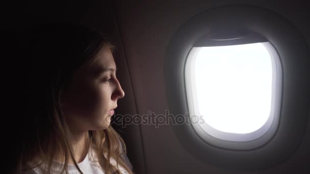 Kız uçak penceresinin yanında oturuyor ve dışarı bakıyor.. - Video, Çekim