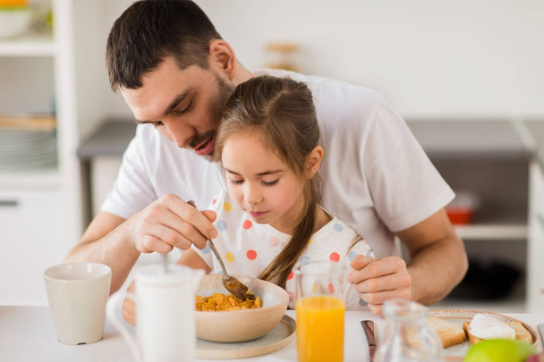 happy family eating flakes for breakfast at home - Φωτογραφία, εικόνα