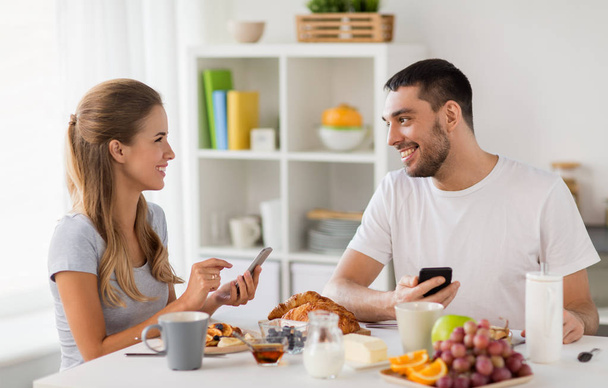 couple with smartphones having breakfast at home - Foto, Imagen