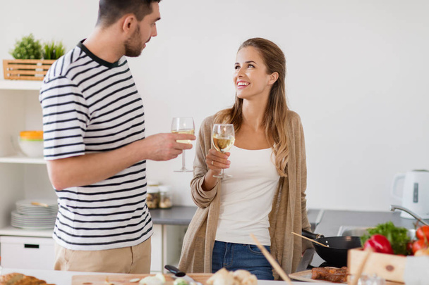 couple cooking food and drinking wine at home - Foto, imagen