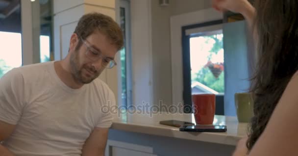 Man and woman using digital tablet and mobile phones in their home kitchen - Materiał filmowy, wideo