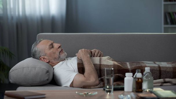 Pensionato di sesso maschile che dorme a letto dopo l'assunzione di farmaci, malattie e assistenza sanitaria
 - Foto, immagini