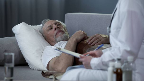 Adult man lying on couch and talking with doctor about health problems, disease - Zdjęcie, obraz