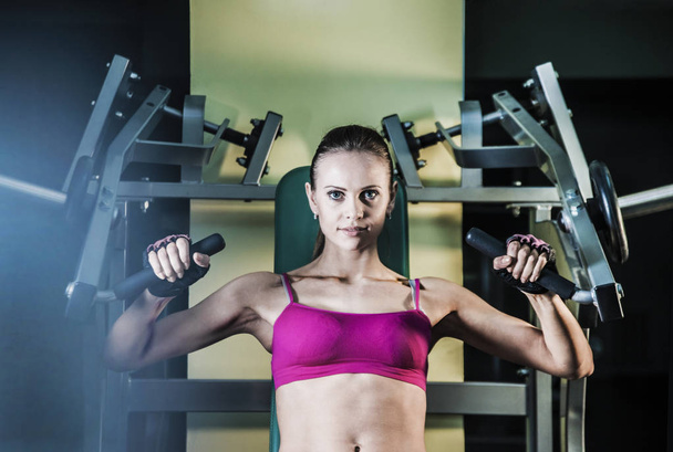 Femme sportive faisant des exercices sur la machine d'entraînement de puissance dans la salle de gym
.  - Photo, image
