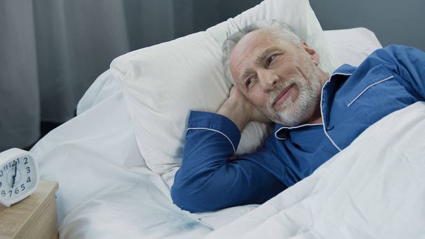 Senior male waking up and smiling after comfortable healthy sleep, health care - Foto, Imagen