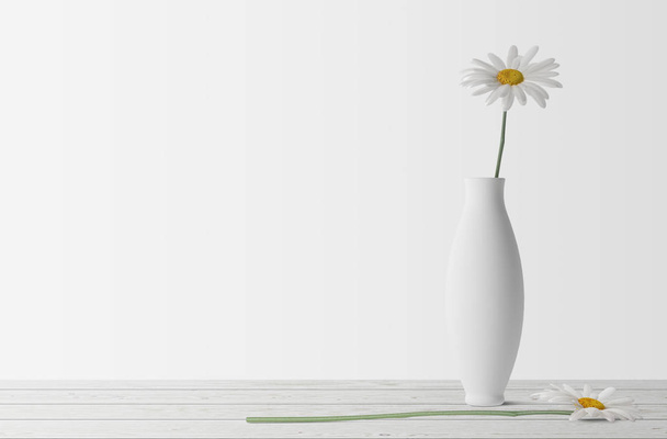 fleur de camomille blanche dans un vase en céramique sur table en bois
  - Photo, image