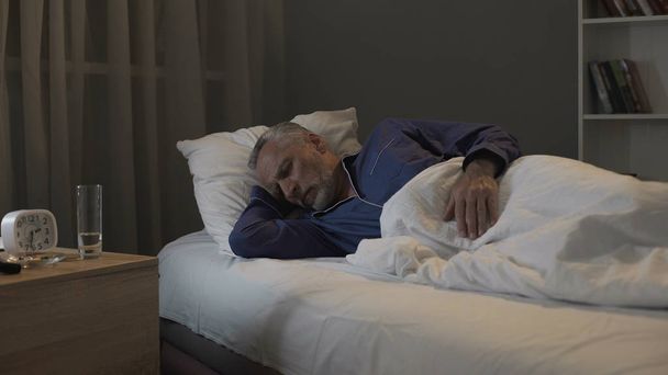Retired man seeing nightmares in his dreams, sleeping in ward of nursing home - Photo, Image