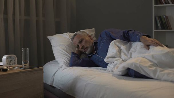 Rentner wartet ungeduldig auf den Morgen und leidet nachts unter Schlaflosigkeit - Foto, Bild