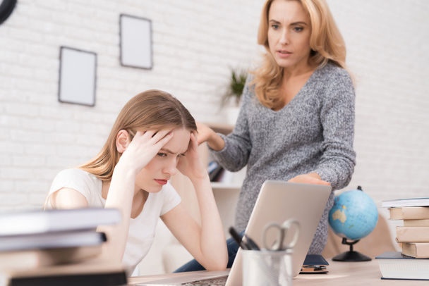 Mom scolds her daughter for a bad job on the laptop. The daughter can not do the school assignment correctly. The woman is angry because of this. She screams at her daughter. - Foto, imagen