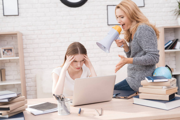 Mom scolds her daughter for a bad job on the laptop. The daughter can not do the school assignment correctly. The woman is angry because of this. She screams at her daughter. - Photo, Image