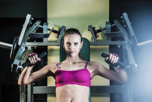 Sports woman doing exercises on power training machine  in the gym.  - Zdjęcie, obraz