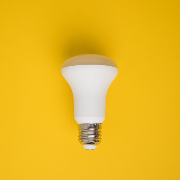 close up view of white light bulb isolated on yellow - Fotografie, Obrázek