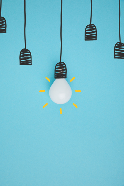 top view of light bulb pretending hanging on lamp holder isolated on blue - Photo, Image