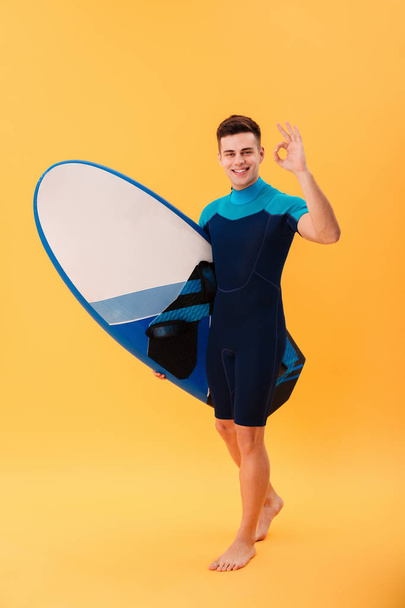 Full length image of happy surfer walking with surfboard - Foto, immagini