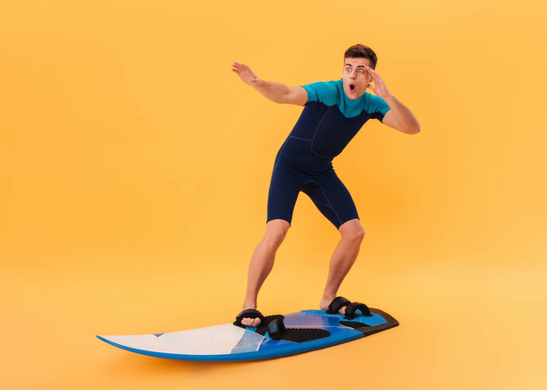 Image of Shocked surfer in wetsuit using surfboard - Zdjęcie, obraz