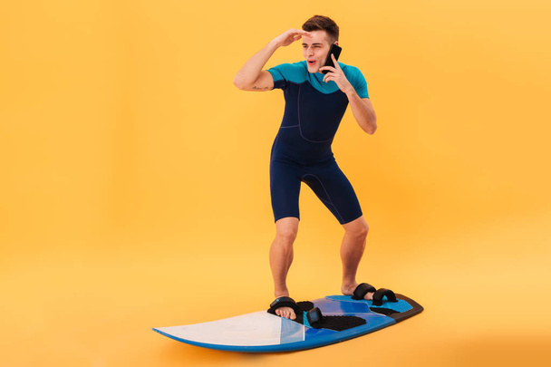 Image of Happy surfer in wetsuit using surfboard - Фото, изображение