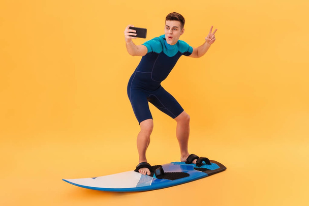 Image of Happy surfer in wetsuit using surfboard - Фото, зображення
