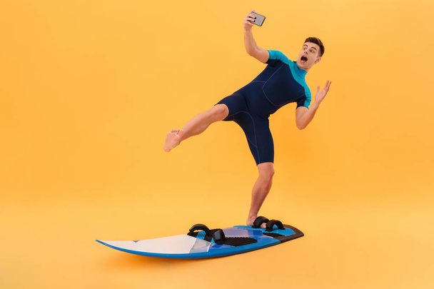 Picture of Playful surfer in wetsuit using surfboard - Fotoğraf, Görsel