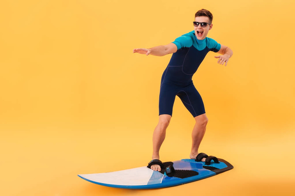 Happy surfer in wetsuit and sunglasses using surfboard - Foto, Imagen