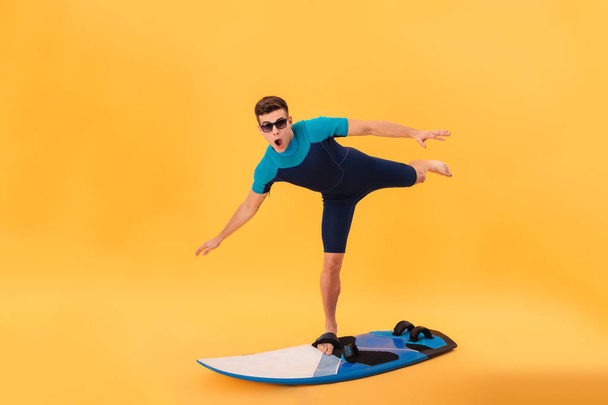 Picture of Funny surfer in wetsuit and sunglasses using surfboard - Foto, Imagem