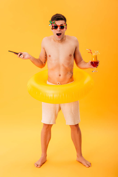 Full-length image of Surprised naked man in shorts and sunglasses - Foto, afbeelding